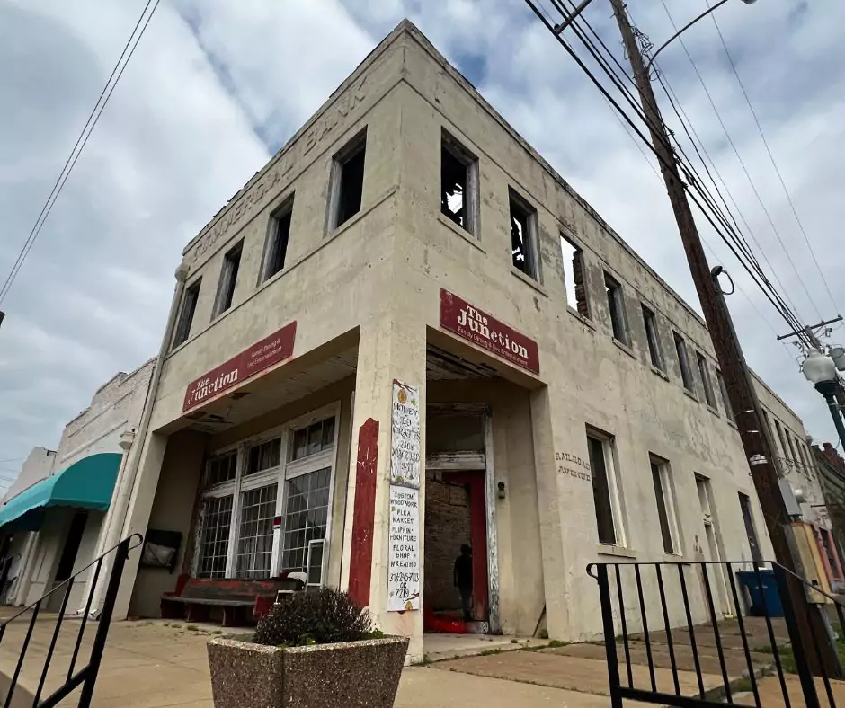 Side angle view of the abandoned Commercial Bank building with faded signage and boarded windows in Arcadia.