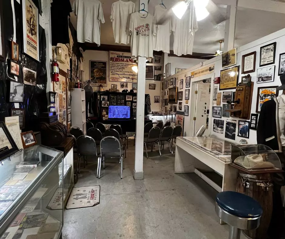 Interior view of the Bonnie and Clyde Ambush Museum in Gibsland, Louisiana, showing memorabilia displays, vintage photos, and a small theater area.