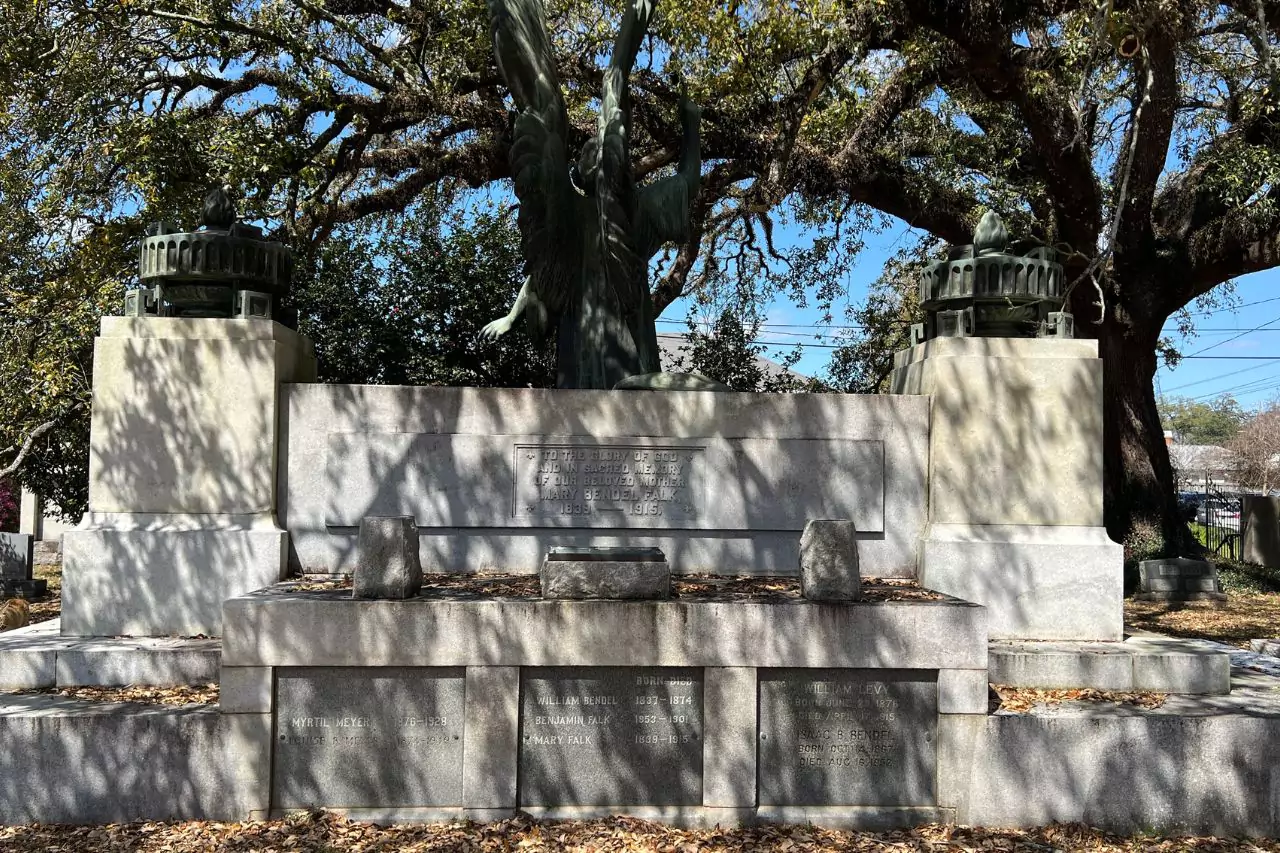 Family Mausoleum Monument with Angel Statue Lafayette Museum cemetery monument with engraved names, large granite structure, and a bronze angel sculpture raised between two urns under sprawling oak trees.