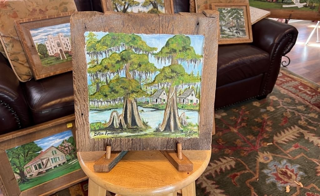 Framed artwork titled “Bayou Rouge” by Henry Watson, showing cypress trees and cottages along a Louisiana bayou.