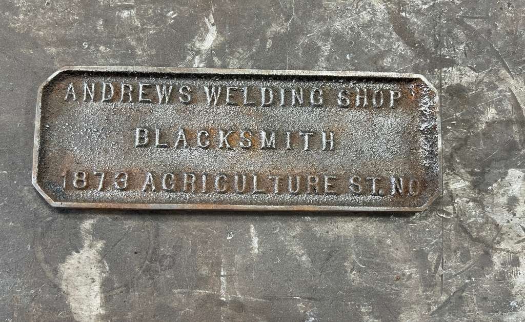 Metal plaque for Andrew’s Welding & Blacksmith Shop, marked with the address 1873 Agriculture Street in New Orleans.
