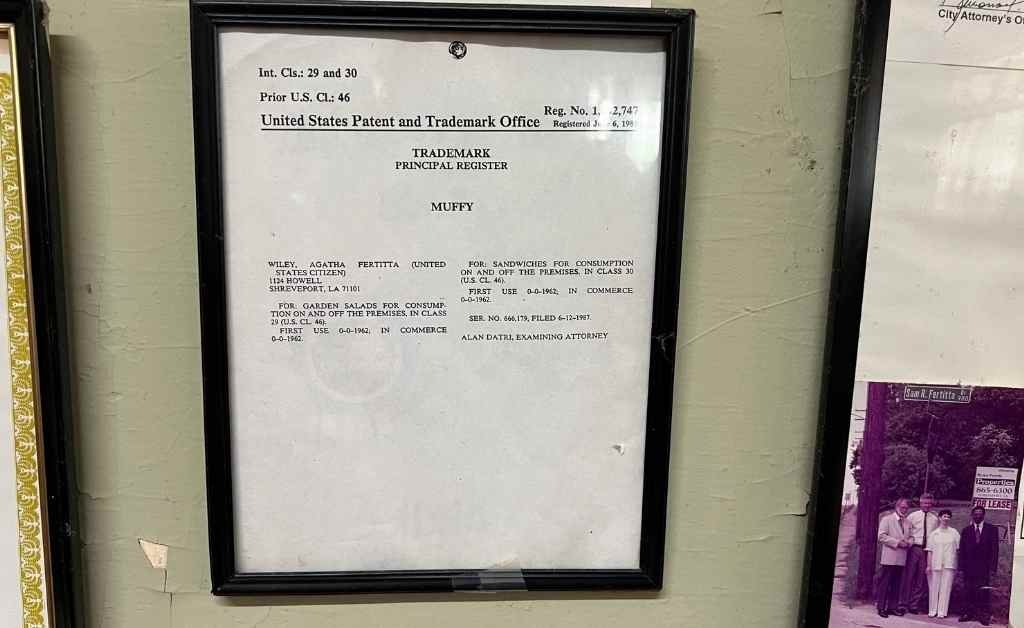Framed United States Patent and Trademark Office certificate registering the Muffy sandwich trademark, displayed inside Fertitta's Deli in Shreveport.
