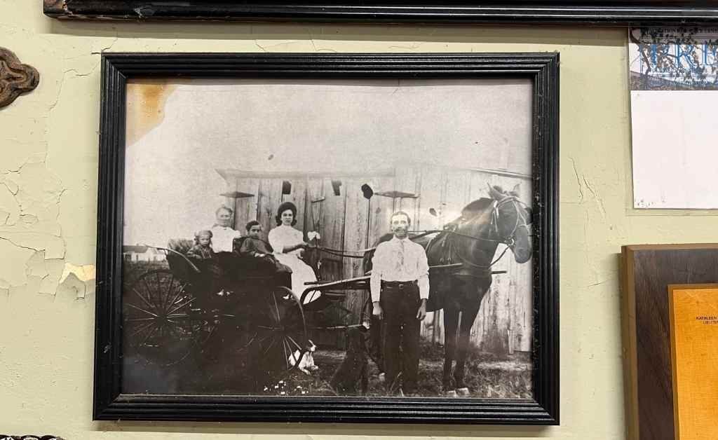 Framed vintage black-and-white photo of early Fertitta family members with a horse and carriage, displayed on the wall inside Fertitta's Deli.