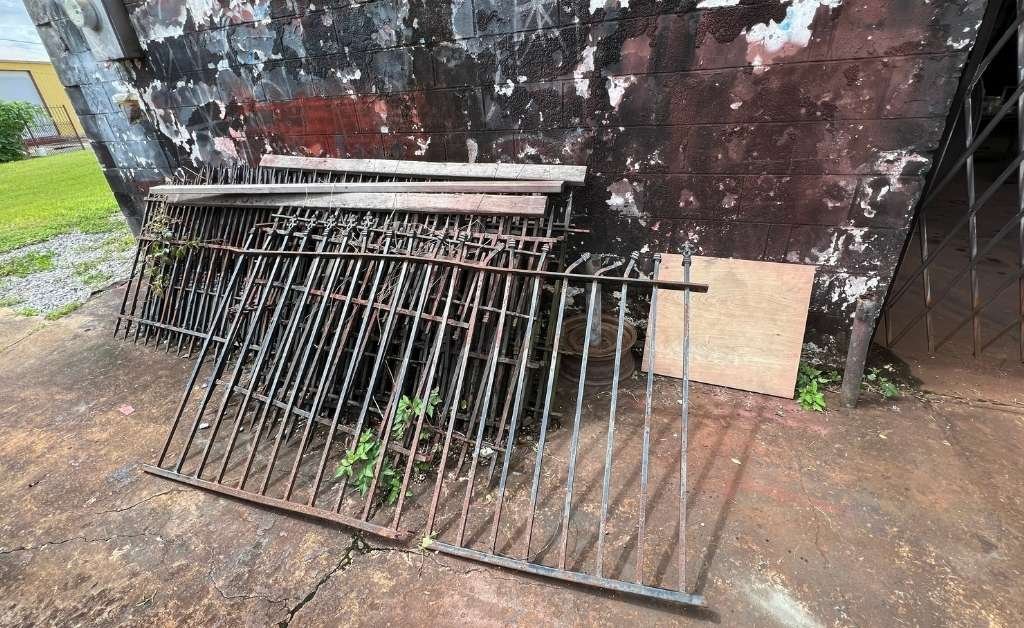 Stacked sections of old wrought iron fences leaning against an exterior wall, awaiting restoration by Darryl Reeves and his team.