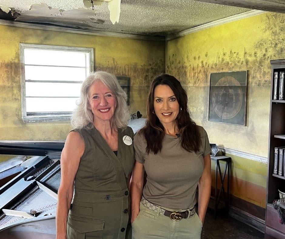 Sandy Rosenthal, founder of Levees.org, and journalist Karen LeBlanc inside the Flooded House Museum in New Orleans, with water-stained walls and a damaged piano behind them, preserved from Hurricane Katrina’s aftermath.