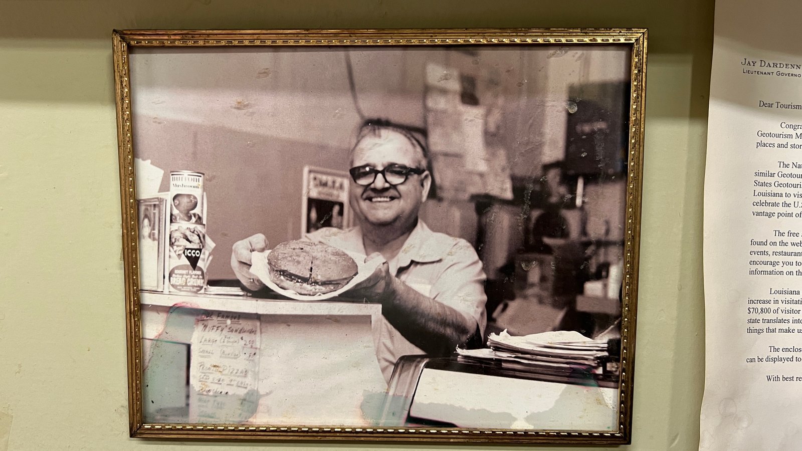 Framed vintage photo of Sam Fertitta behind the counter at Fertitta's Deli, recognized as the founder of the deli and creator of its signature Muffy sandwich legacy