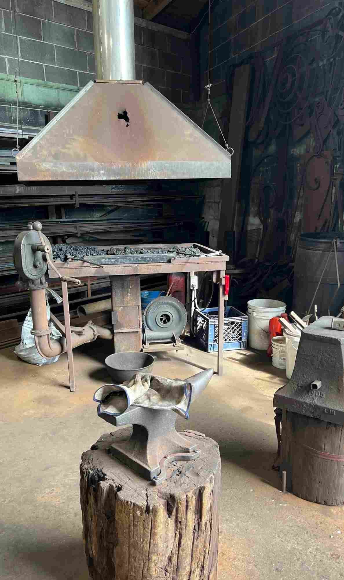 Blacksmithing forge with chimney hood, coal fire bed, and anvil inside Darryl Reeves’ New Orleans workshop.