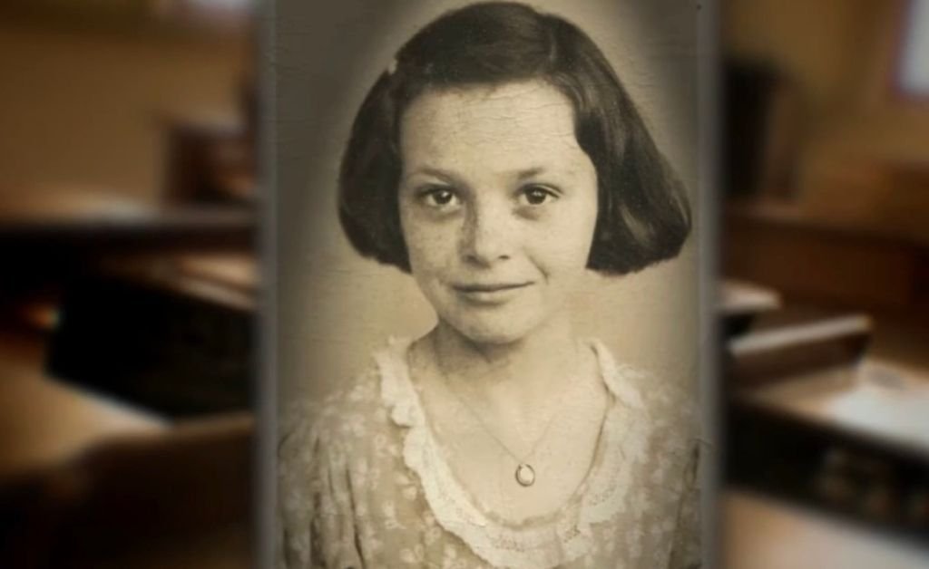 A childhood portrait of Mavis Arnaud Fruge as a young schoolgirl, wearing a floral dress and necklace, symbolizing her early Louisiana French roots.
