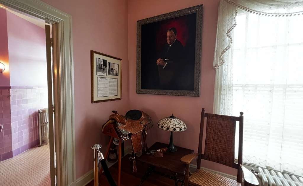 A cozy corner of the Jimmie Davis Room at the Old Governor’s Mansion, featuring a portrait of Governor Jimmie Davis, a western saddle on display, and framed memorabilia that reference his famous horse, Sunshine.