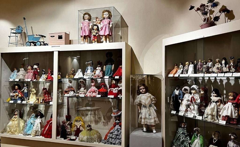 Extensive doll exhibit at the Opelousas Museum featuring vintage and cultural dolls in glass cases, including period attire and regional representation.