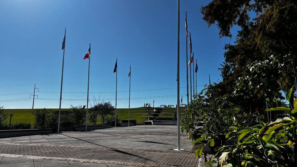 Flag-lined plaza and walkway in Rivertown Kenner on a clear day.