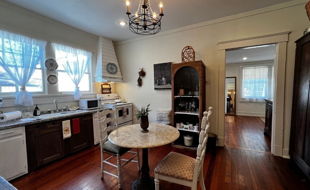 Kitchen inside the Clancy House with vintage cabinetry, a small dining table, open shelving, and restored historic details in a warm, lived-in space.