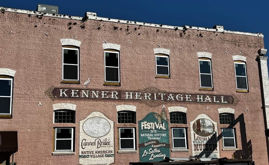 Exterior of Kenner Heritage Hall in Rivertown Kenner, featuring historic brickwork and painted murals highlighting local history and culture.
