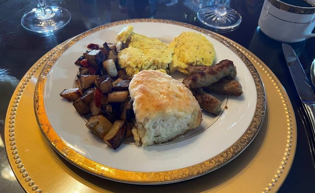 Home cooked breakfast at The Caldwell House Bed and Breakfast featuring scrambled eggs, sausage, roasted potatoes, and a freshly baked biscuit.