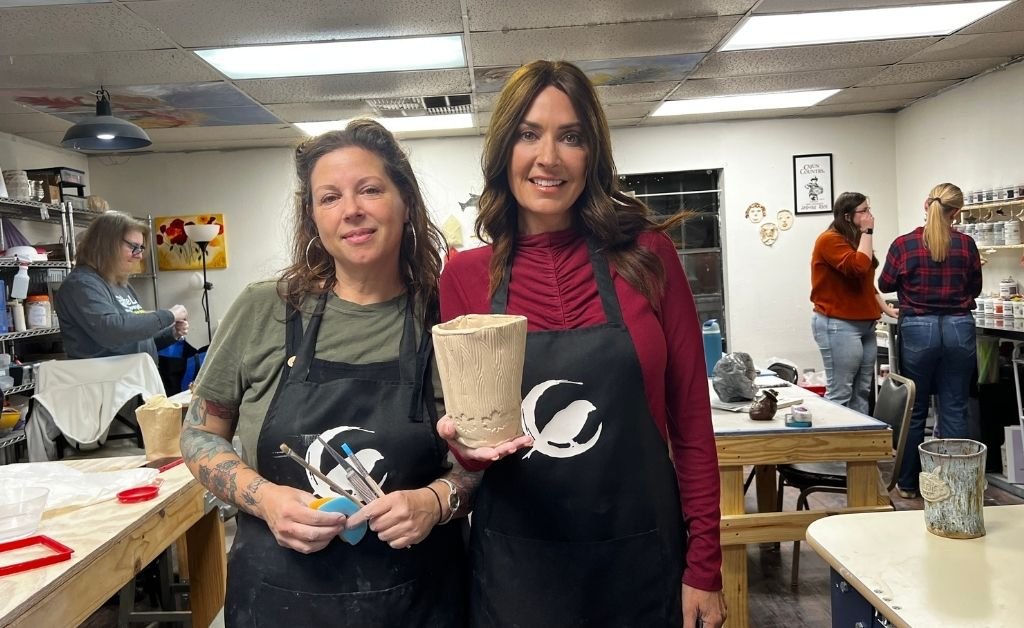 Karen LeBlanc holding a handmade clay piece with an instructor inside Wrenworks Art Studio in Rivertown Kenner.