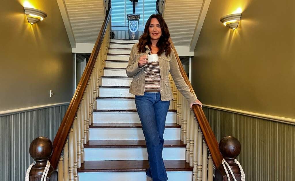 Karen LeBlanc standing on the central staircase at The Caldwell House Bed and Breakfast in Abbeville, Louisiana.