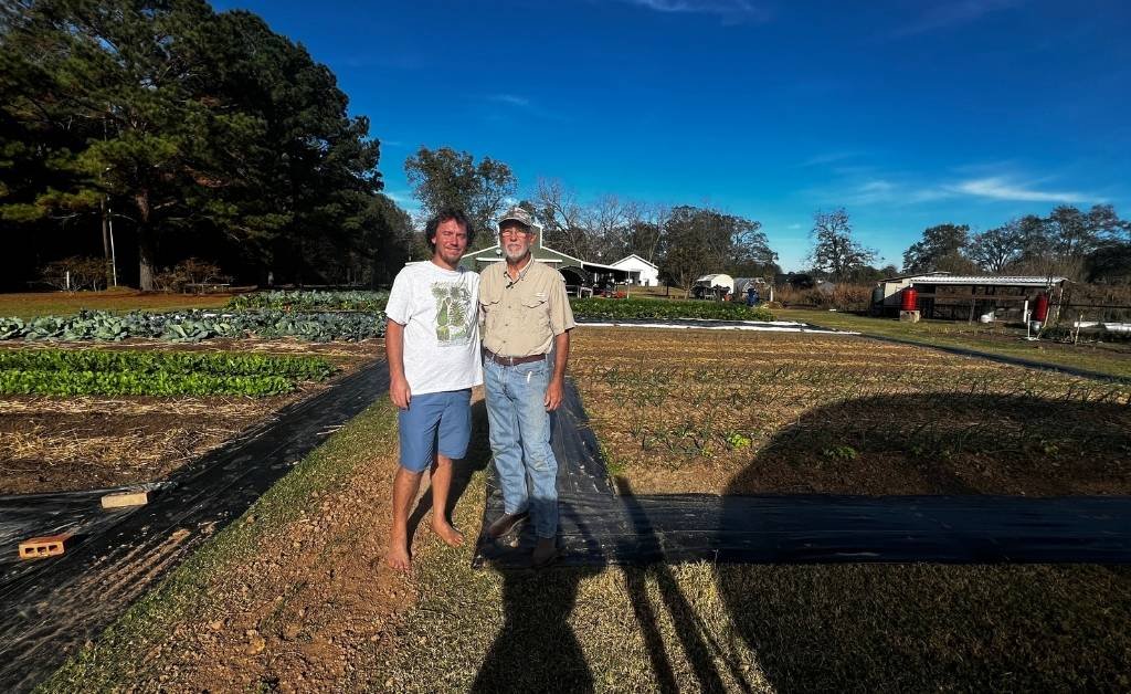 Larry Allain and his son Andre Allain standing together in the vegetable fields at Cajun Prairie Farm in Arnaudville, Louisiana.