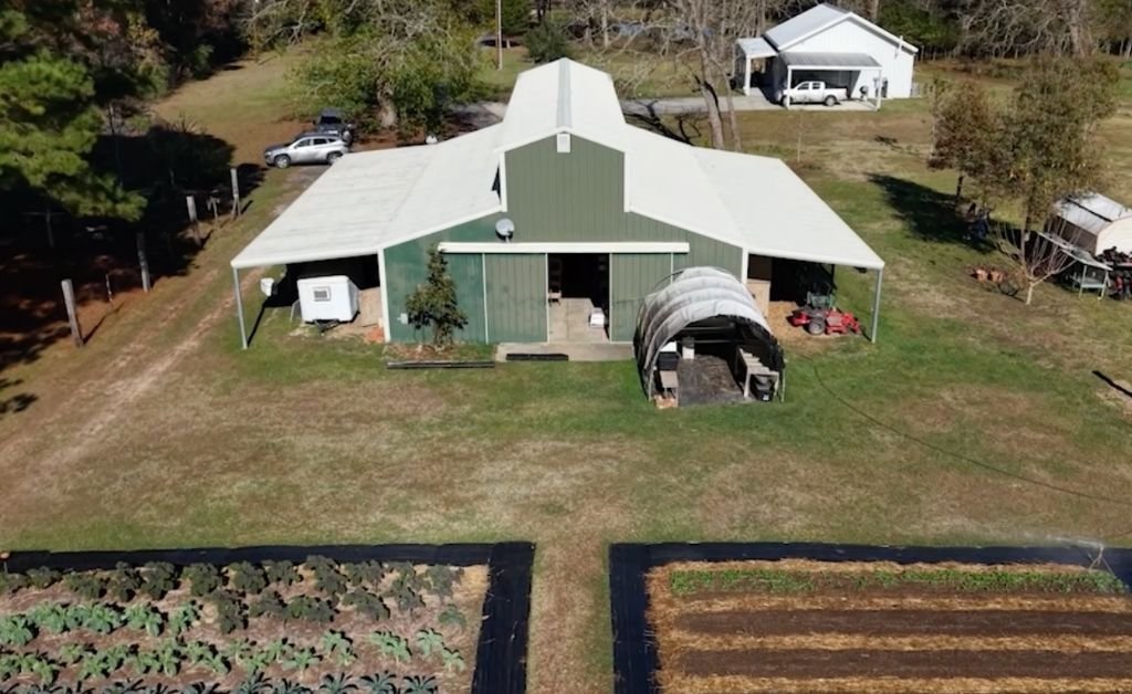 Aerial view of the barn and garden beds at Cajun Prairie Farm in Arnaudville, Louisiana, with cultivated rows in the foreground.