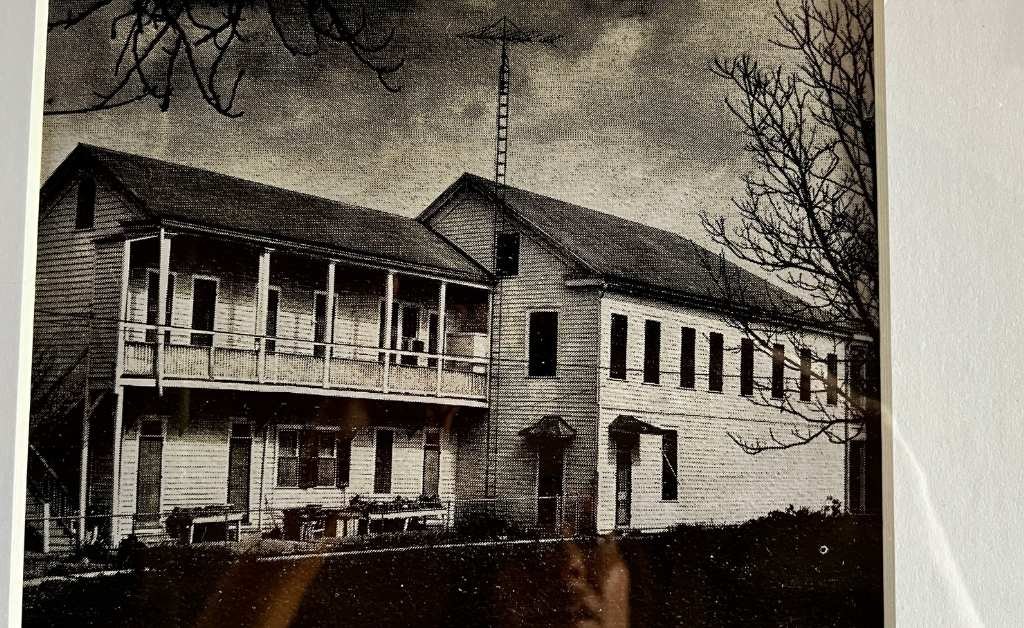 Historic black-and-white photograph of the original Klaus Building in Washington, Louisiana, showing the two-story structure with front gallery and residential upper level.