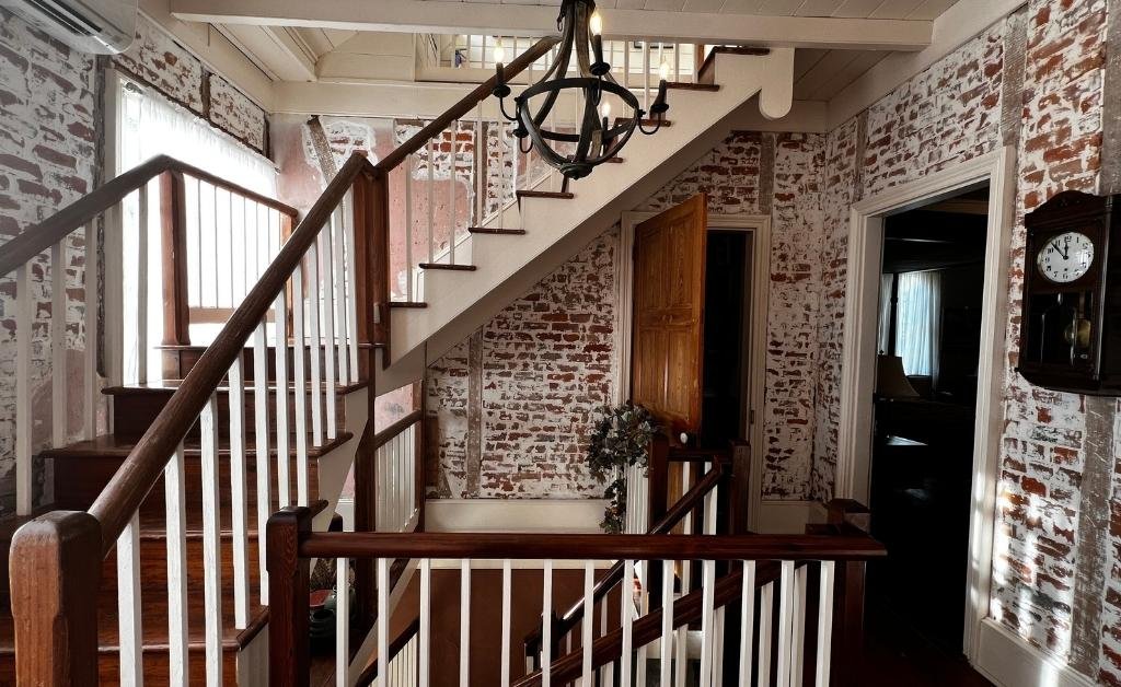 Interior staircase at Maison Stephanie showing exposed brick walls, wooden railings, and historic architectural details.