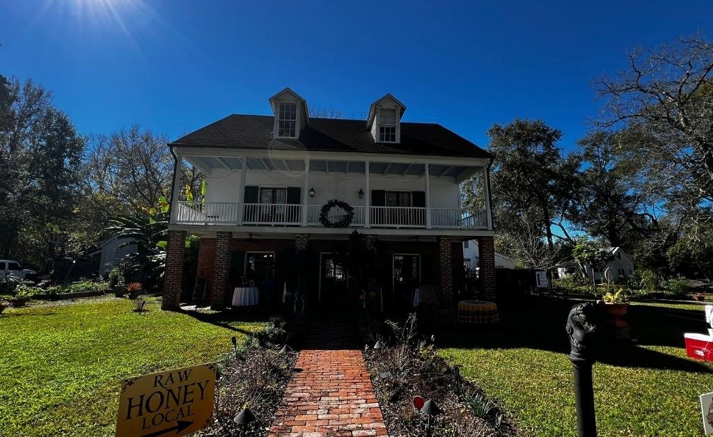 Front exterior of Maison Stephanie, a historic two-story home in Arnaudville, Louisiana, set along a brick walkway and garden.