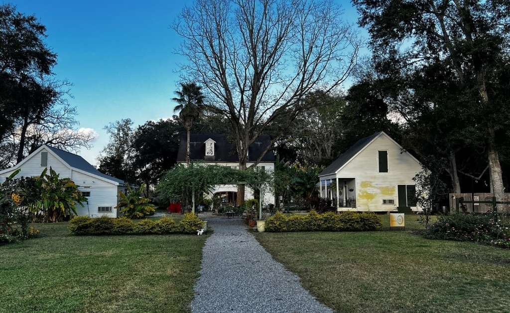 Garden path leading to Maison Stephanie with the main house and cottages set among trees and landscaped grounds.
