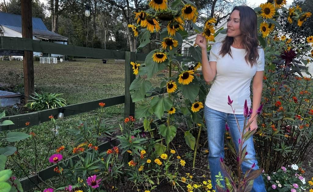 Karen LeBlanc standing among sunflowers and garden flowers on the grounds of Maison Stephanie in Arnaudville.
