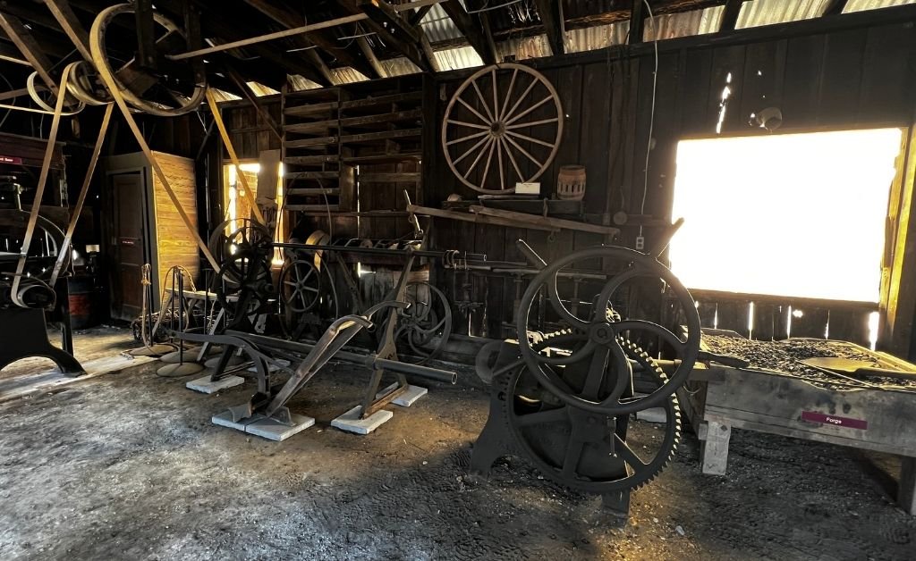 Historic belt-driven machinery and forge equipment inside the Sam Guarino Blacksmith Shop Museum in Abbeville, Louisiana.