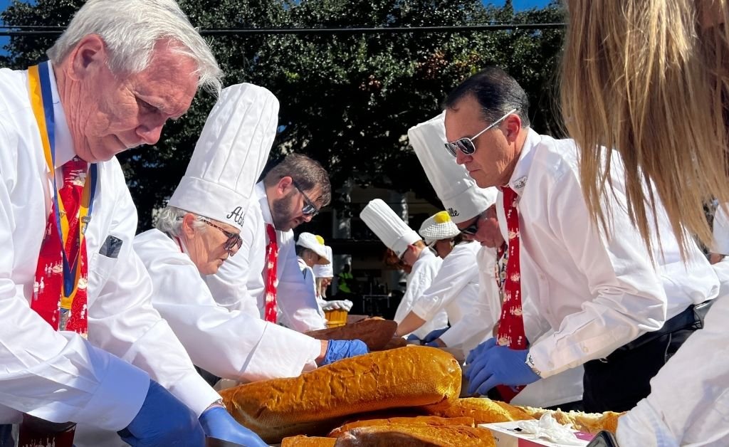 Members of the Omelette Confrérie slice French bread for serving during the Giant Omelette Celebration in Abbeville, Louisiana