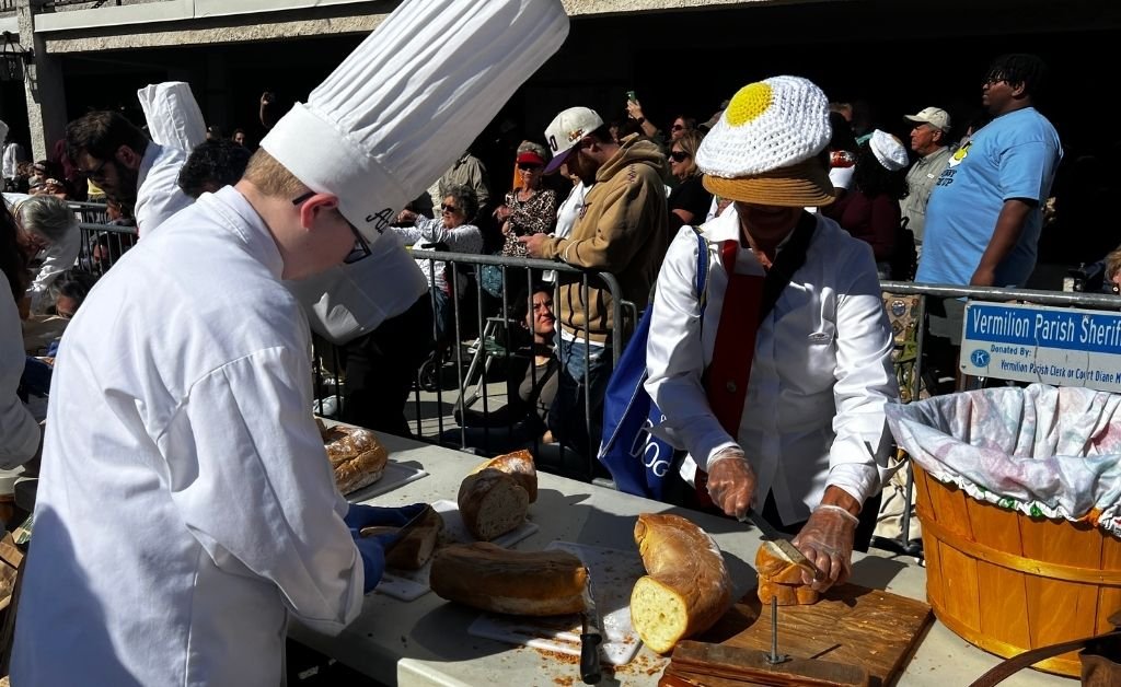 Volunteers slice French bread for serving during the Giant Omelette Celebration in downtown Abbeville, Louisiana