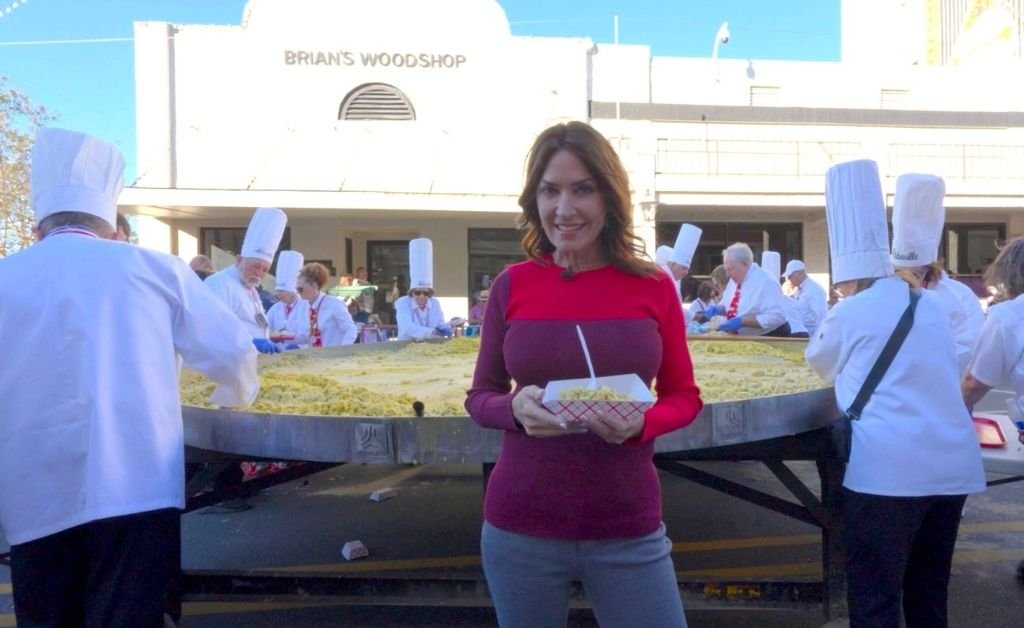 Karen LeBlanc holds a serving of the giant omelette as chefs cook behind her at the Giant Omelette Celebration in downtown Abbeville.