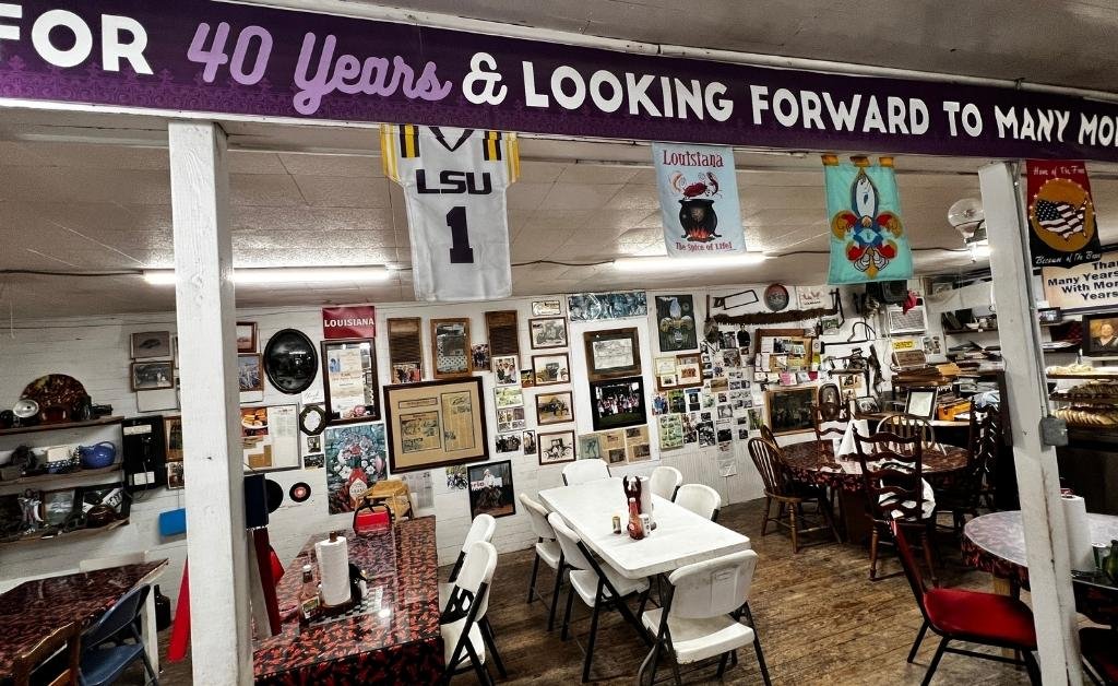 Dining area inside Suire's Grocery and Restaurant with community tables and framed photos on the walls