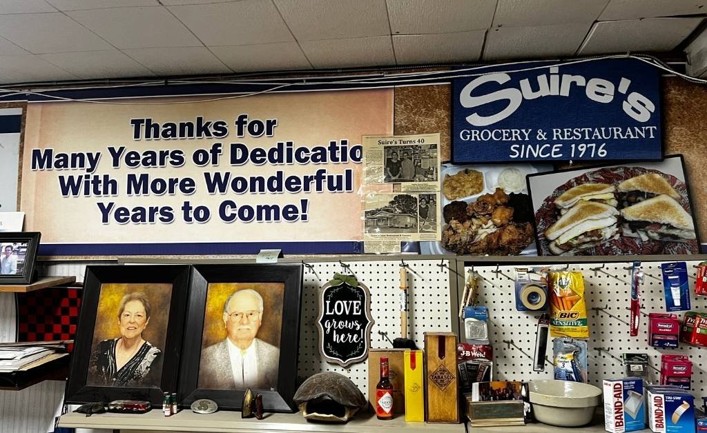 Interior wall display at Suire's Grocery and Restaurant featuring family photos, memorabilia, and a since 1976 sign