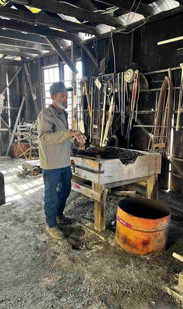 Blacksmith tending the forge inside the Sam Guarino Blacksmith Shop Museum in Abbeville, Louisiana.