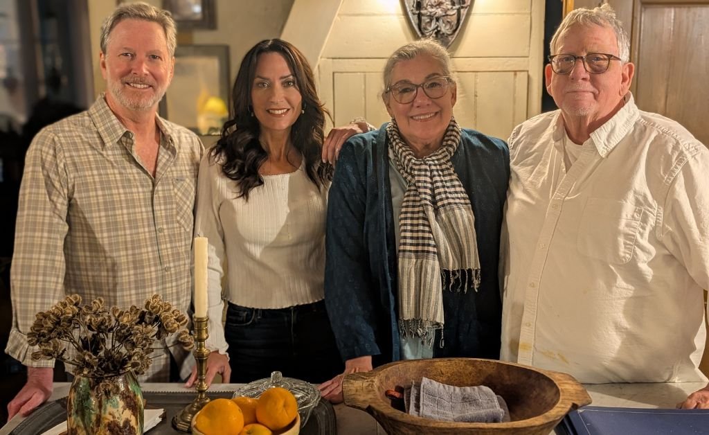 From left to right: Ryan the videographer, host Karen, and Maison Madeleine owners Madeleine Cenac and Walt Adams standing together in a rustic kitchen setting.