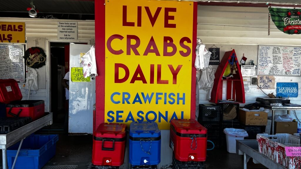 A dark brick monument on a grassy roadside reading "WESTWEGO FOUNDED 1892" in gold capital letters. A Blue Star Memorial marker and a large, leafy tree stand in the background under a clear blue sky.