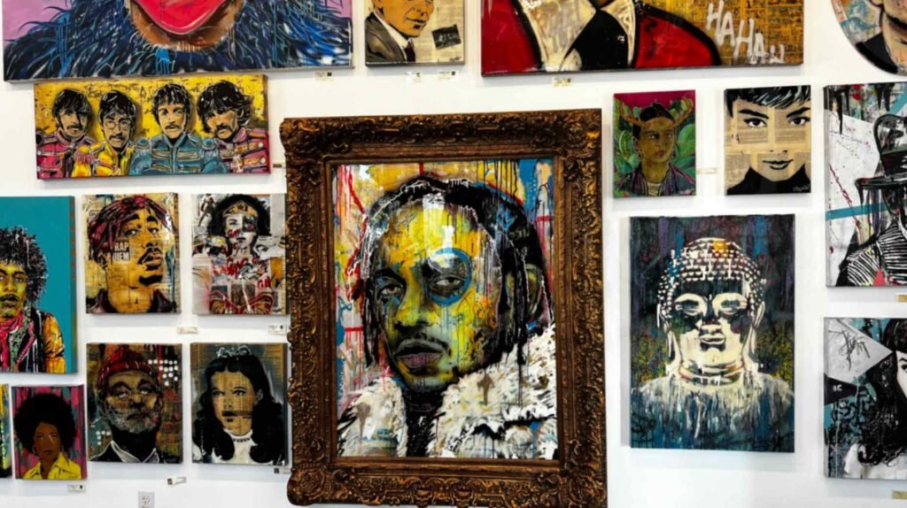 A gallery wall covered in colorful, stylized pop art portraits including Kendrick Lamar in a large ornate gold frame, The Beatles, Frida Kahlo, and Tupac Shakur.