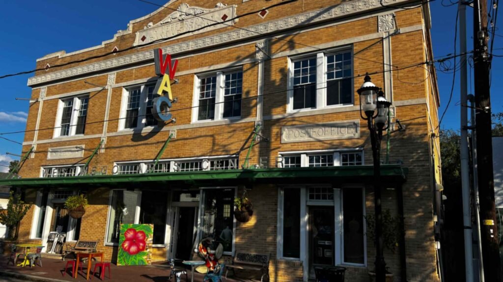 A close-up, low-angle shot of a black decorative street sign that reads "Sala Av" and "Historic Salaville" against a clear blue sky and leafy green trees.
