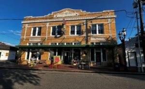 Historic brick building in Westwego, Louisiana, housing Joshua Wingerter’s gallery inside a former bank, featuring large windows, vintage architectural details, and colorful outdoor art displays along the street.