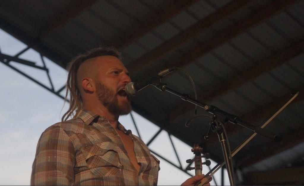 Jourdan Thibodeaux singing into a microphone on stage.