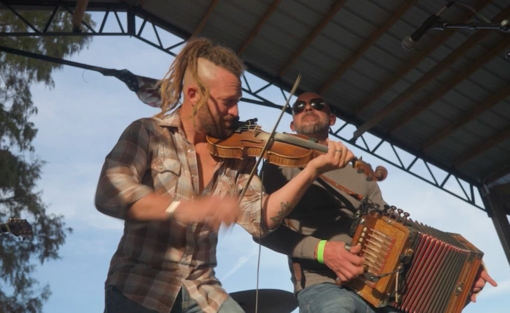 Jourdan Thibodeaux playing the fiddle alongside a band member playing a German accordion.