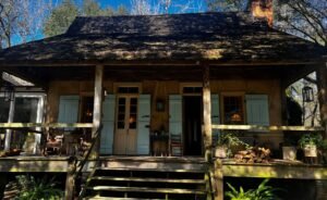 The wooden front porch and light blue shutters of the historic Maison Madeleine French Creole cottage in Louisiana.
