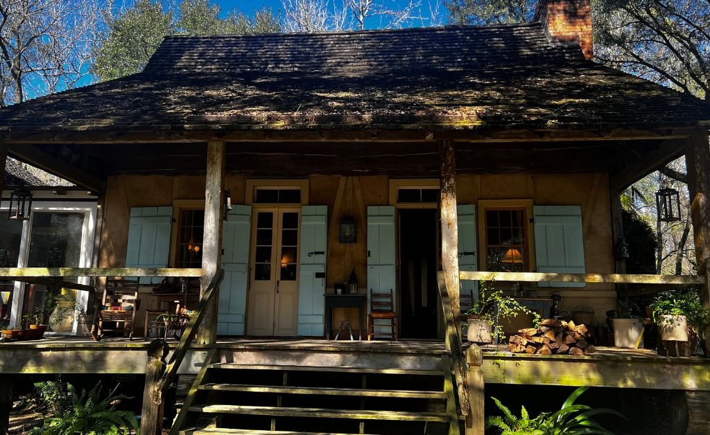 The wooden front porch and light blue shutters of the historic Maison Madeleine French Creole cottage in Louisiana.
