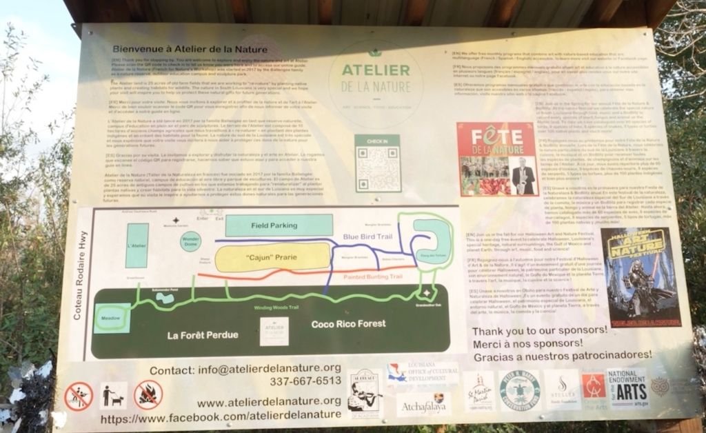 A large, informative outdoor sign at Atelier de la Nature features a detailed map of the nature reserve's trails, including the "Cajun" Prairie, Blue Bird Trail, and Coco Rico Forest.