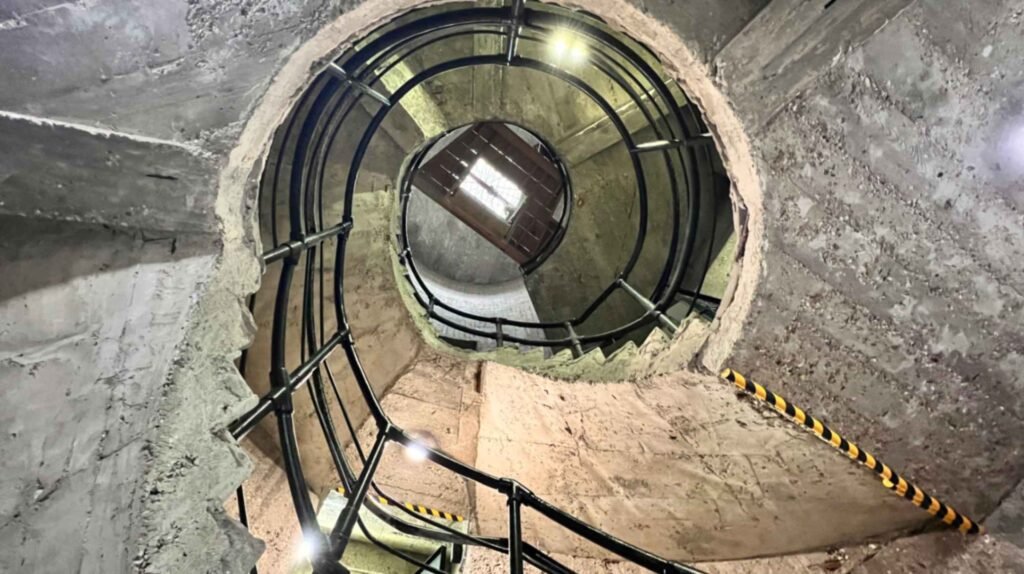 A low-angle view looking up the three-story reinforced concrete spiral staircase inside the historic DeRidder Gothic Jail, also known as the Hanging Jail.
