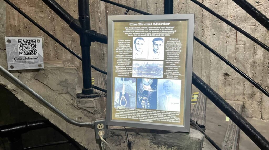 An informational plaque titled "The Brutal Murder" is mounted on a concrete wall inside the DeRidder Gothic Jail, detailing the 1928 double execution alongside historical photos and a QR code for "Gothic Architecture